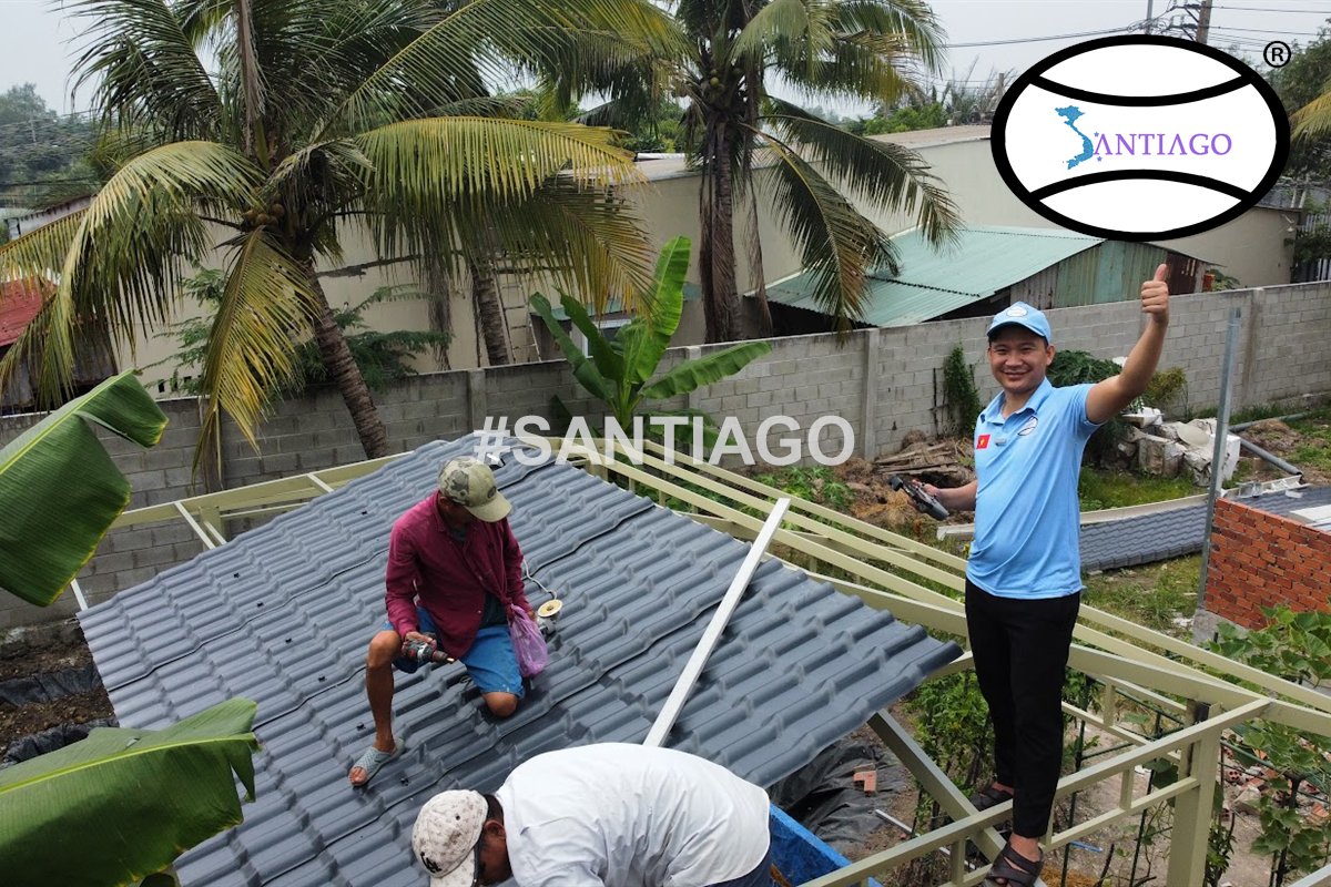 Thợ đang lợp ngói nhựa xám trên mái nhà giữa vườn dừa